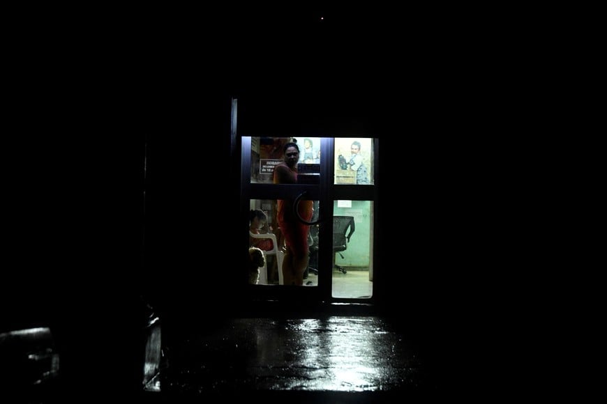 A woman peers from a door as the energy grid suffers a complete blackout while Hurricane Rafael makes landfall in Artemisa province as a category three hurricane, in Havana, Cuba November 6, 2024. REUTERS/Norlys Perez