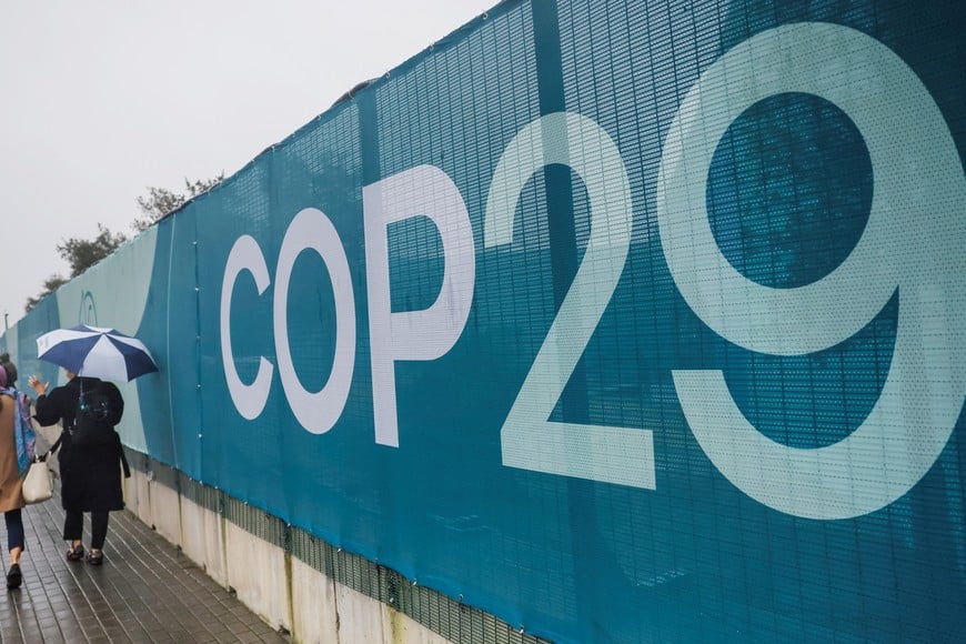 People with an umbrella walk near the United Nations climate change conference COP29 venue in Baku, Azerbaijan November 14, 2024. REUTERS/Maxim Shemetov