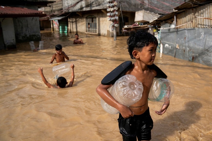 Children play along a flooded street following super typhoon Man-Yi, in Cabanatuan, Nueva Ecija, Philippines, November 18, 2024. REUTERS/Lisa Marie David     TPX IMAGES OF THE DAY