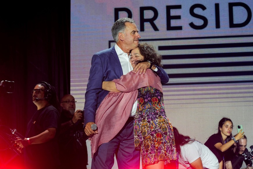 Uruguay's centre-left presidential candidate Yamandu Orsi embraces his wife Laura Alonso Perez onstage following early results of the presidential election run-off between Orsi and the candidate of the ruling conservative coalition Alvaro Delgado, in Montevideo, Uruguay November 24, 2024. REUTERS/Mariana Greif  REFILE - REMOVING "CONCEDES DEFEAT".