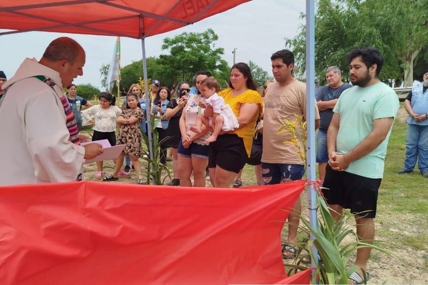 En un gazebo, a orillas del río, el padre Sergio Capoccetti prepara a la familia para el bautismo en el río.