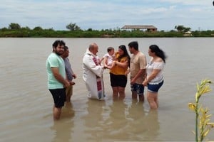 Dentro del agua, el sacerdote está a punto de practicar el rito de bautismo.