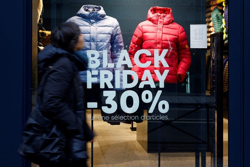 A woman walks past a Black Friday sale sign displayed on a shop window in Paris, France, November 23, 2023. REUTERS/Sarah Meyssonnier