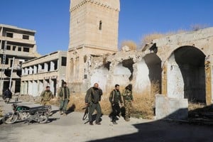 Rebel fighters walk in Maarat al-Numan in Idlib province, Syria December 1, 2024. REUTERS/Mahmoud Hassano