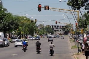 Tres motociclistas cruzan un semáforo en rojo. El registro gráfico es en el barrio Villa María Selva. Crédito: José Vittori