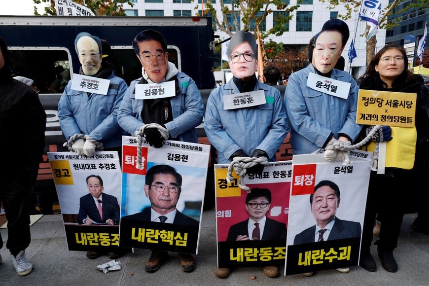 Protesters wear masks depicting South Korean President Yoon Suk Yeol, outgoing Defense Minister Kim Yong-hyun, People Power Party's leader Han Dong-hoon and Choo Kyung-ho at a rally calling for the impeachment of South Korean President Yoon Suk Yeol, who declared martial law, which was reversed hours later, near the National Assembly in Seoul, South Korea, December 7, 2024. REUTERS/Kim Soo-hyeon