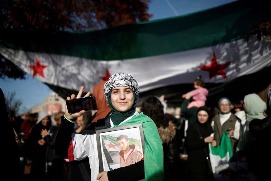 A woman holds a mobile phone as people celebrate in Lafayette Square outside the White House, after Syrian rebels announced that they have ousted President Bashar al-Assad, in Washington, U.S., December 8, 2024. REUTERS/Benoit Tessier