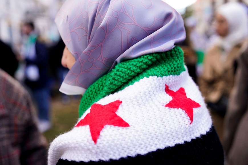 A person wears a crocheted Syrian opposition flag during a demonstration celebrating the fall of Bashar Al-Assad regime outside the Syrian embassy in Madrid, Spain, December 8, 2024. REUTERS/Ana Beltran