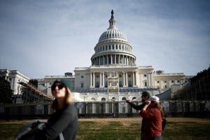 People walk past the U.S. Capitol with an inaugural platform under construction in front of it, in Washington, U.S., December 8, 2024. REUTERS/Benoit Tessier