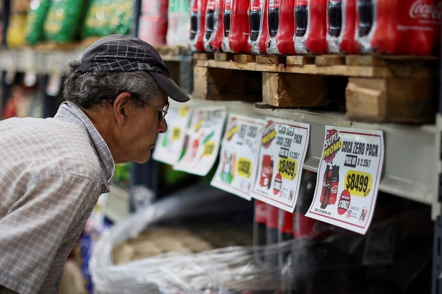 A man checks soda prices in a supermarket, as Argentina is battling with an annual inflation heading towards 200%, in Buenos Aires, Argentina December 13, 2023. REUTERS/Agustin Marcarian