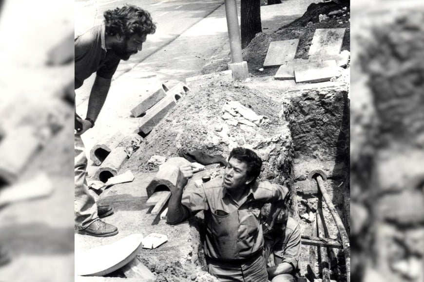 Un joven cronista de El Litoral habla con los obreros que hacían las excavaciones en calle Suipacha. Técnicos de la Epe primero y de la firma Pirelli luego se tardaron un mes en dar con el lugar de la falla.  Eduardo Salva- Archivo El Litoral