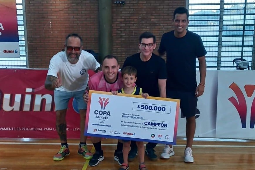 El premio para los varones. El capitán de Porvenir Talleres de Villa Constitución recibe el cheque de manos de Daniel Di Lena, en nombre del Gobierno de Santa Fe y la Lotería. Acompañan Gastón Albornoz (presidente de la Asociación Santafesina de Handball) y Nicolás Iparraguirre en nombre de la Secretaría de Deportes de la Provincia Foto: Gentileza Santa Fe Producciones/Mario Bossi