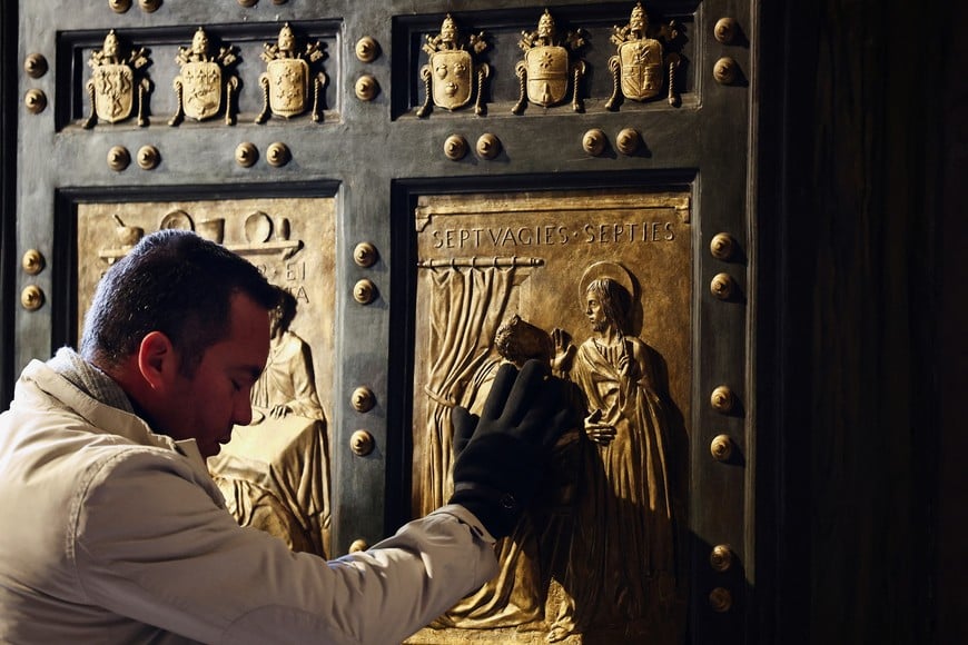 A person touches the Holy Door in Saint Peter's Basilica, a day after Pope Francis opened it for the 2025 Catholic Holy Year, or the Jubilee, at the Vatican December 25, 2024. REUTERS/Yara Nardi