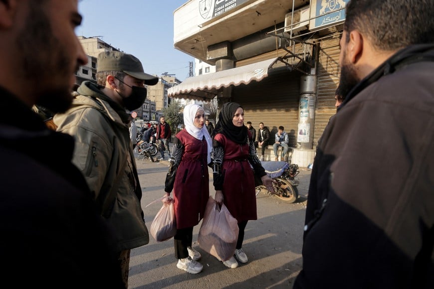 Women talk with fighters of the ruling Syrian body, after dissent surfaced in the city of Homs, north of Damascus, and state media reported that police imposed an overnight curfew on Wednesday night, following unrest linked to demonstrations that residents said were led by members of the Alawite and Shi'ite religious communities, in Homs, Syria December 26, 2024. REUTERS/Khalil Ashawi     TPX IMAGES OF THE DAY