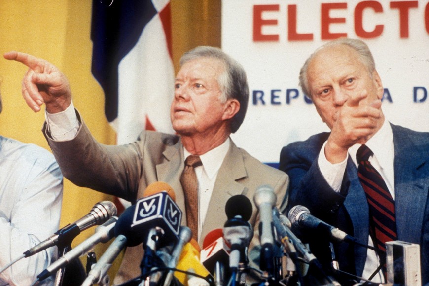 FILE PHOTO: Former U.S. Presidents Jimmy Carter and Gerald Ford point in different directions while calling on reporters wanting to ask questions at a press conference in Panama City, Panama, May 5, 1989.  REUTERS/Dematteis/File Photo