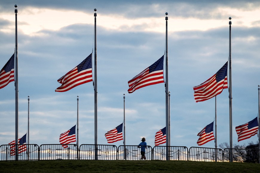 A jogger passes flags flying at half-staff at the Washington Monument on the National Mall following the death of former U.S. President Jimmy Carter, in Washington, U.S., December 30, 2024.  REUTERS/Kevin Lamarque