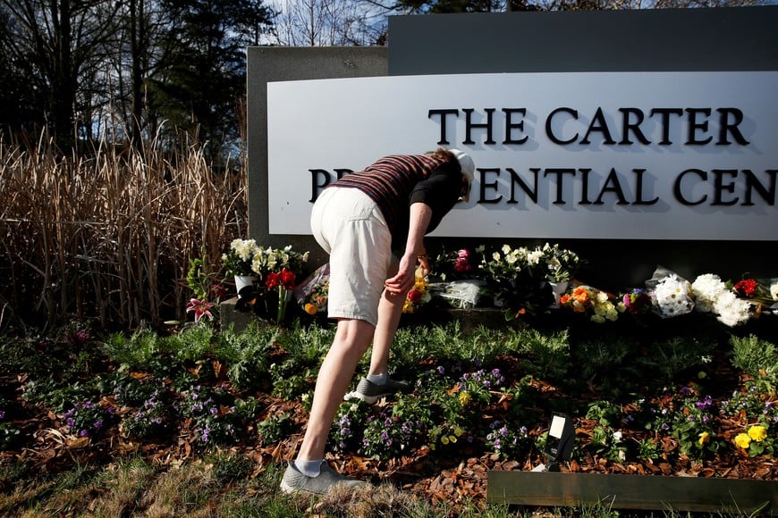 A woman pays respects to former U.S. President Jimmy Carter, who died at the age of 100, by the sign of The Carter Presidential Center, in Atlanta, Georgia, U.S. December 30, 2024. REUTERS/Octavio Jones