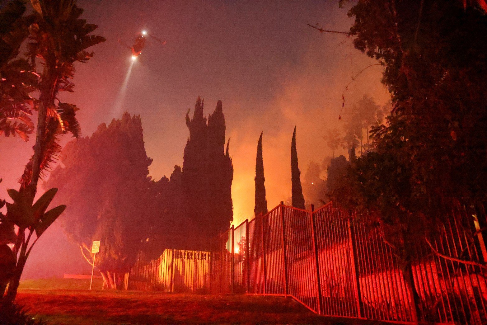 Un helicóptero vuela, mientras el humo se eleva desde el Sunset Fire en las colinas que dominan el barrio de Hollywood de los Ángeles. Créditos: David Swanson