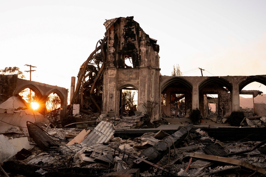 Sun sets behind the remains of a church destroyed by the Palisades Fire in the Pacific Palisades neighborhood in Los Angeles, California, U.S. January 11, 2025. REUTERS/David Ryder