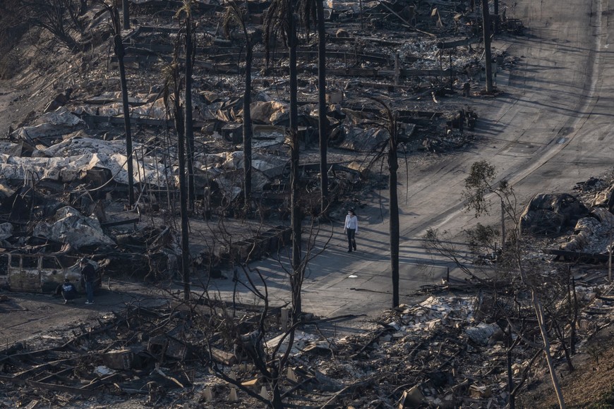 A woman walks past the remains of homes destroyed by the Palisades Fire in the Pacific Palisades neighborhood in Los Angeles, California, U.S. January 11, 2025. REUTERS/Carlos Barria     TPX IMAGES OF THE DAY