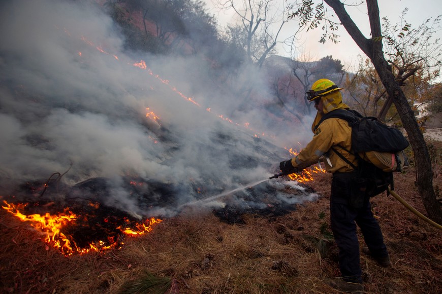 A firefighter battles the Palisades Fire, one of several simultaneous blazes that have ripped across Los Angeles County, in Mandeville Canyon, a neighborhood of Los Angeles, California, U.S., January 11, 2025. REUTERS/Ringo Chiu