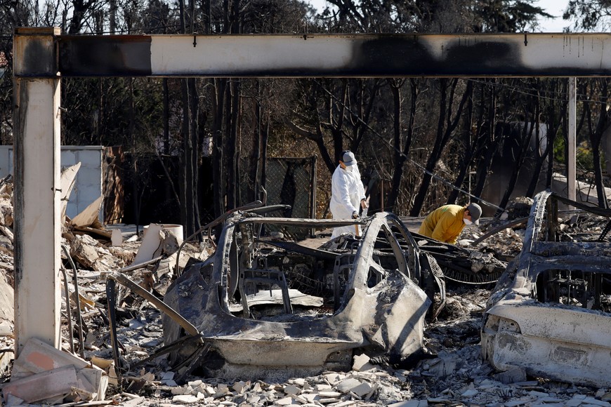 Residents dig through the remains of their home in the Pacific Palisades, after the Palisades Fire burned many homes, in Los Angeles County, California, U.S., January 12, 2025. REUTERS/Daniel Dreifuss