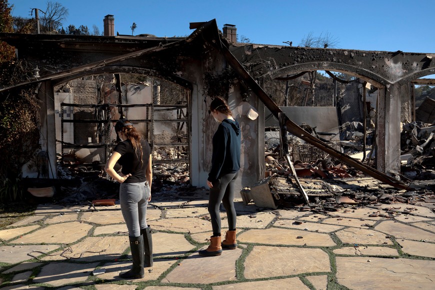 Jessica Davis and Veronica Ban, with Boomer's Buddies Rescue, look for a resident's missing cat while retrieving pets for evacuated residents in an area affected by the Palisades Fire near Pacific Palisades in Los Angeles, California, U.S. January 12, 2025. REUTERS/David Ryder