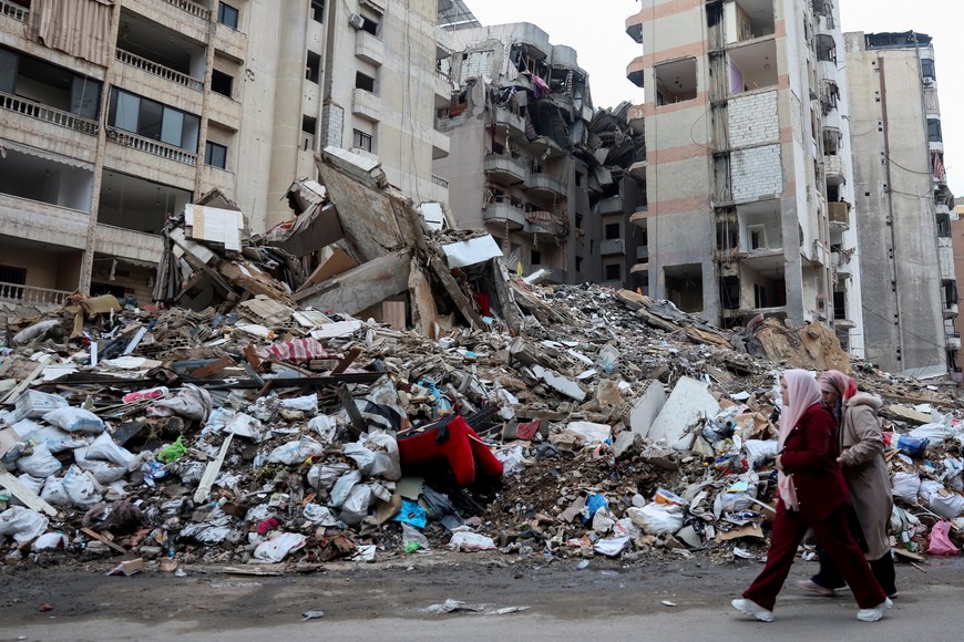 People walk past a damaged site, after the Israeli prime minister's office said on Friday that Israeli forces will remain in southern Lebanon beyond a 60-day deadline stipulated in a ceasefire deal with Hezbollah because its terms have not been fully implemented, in Beirut's southern suburbs, January 24, 2025. REUTERS/Mohamed Azakir