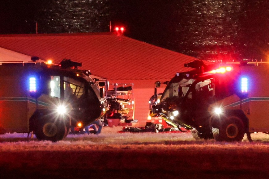 Bodies lie on the ground next to emergency vehicles, near the site of the crash after American Eagle flight 5342 collided with a Black Hawk helicopter while approaching Reagan Washington National Airport and crashed into the Potomac River, outside Washington, U.S., January 30, 2025. REUTERS/Carlos Barria