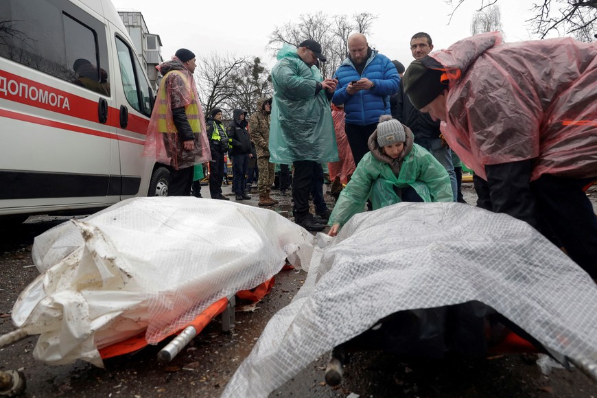 People stand next to the bodies found under debris at the site of an apartment building hit by a Russian missile strike, amid Russia's attack on Ukraine, in Poltava, Ukraine February 1, 2025. REUTERS/Sofiia Gatilova