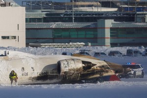 An emergency responder works around an aircraft on a runway, after a plane crash at Toronto Pearson International Airport in Mississauga, Ontario, Canada, February 17, 2025. REUTERS/Cole Burston