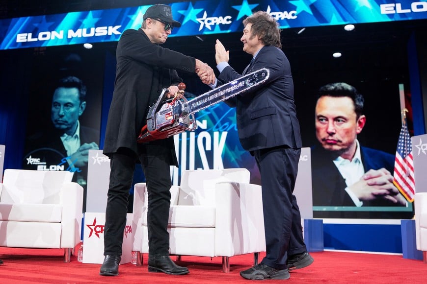 Elon Musk shakes hands with President of Argentina Javier Milei while holding a chainsaw given to him by Milei during the Conservative Political Action Conference (CPAC) in National Harbor, Maryland, U.S., February 20, 2025. REUTERS/Nathan Howard