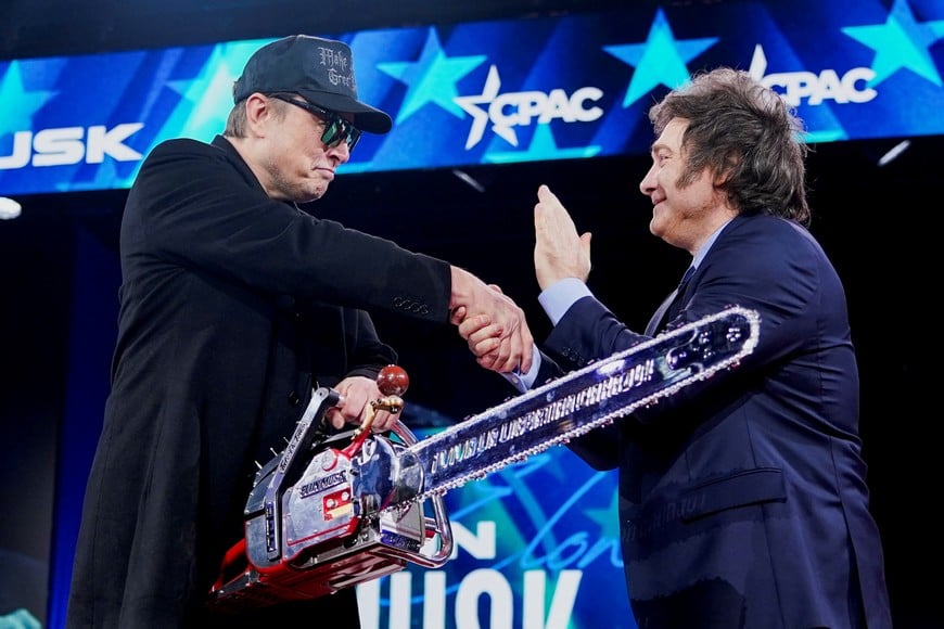 Elon Musk holds a chainsaw and shakes hands with Argentina's President Javier Milei as they attend the Conservative Political Action Conference (CPAC) in National Harbor, Maryland, U.S., February 20, 2025. REUTERS/Nathan Howard