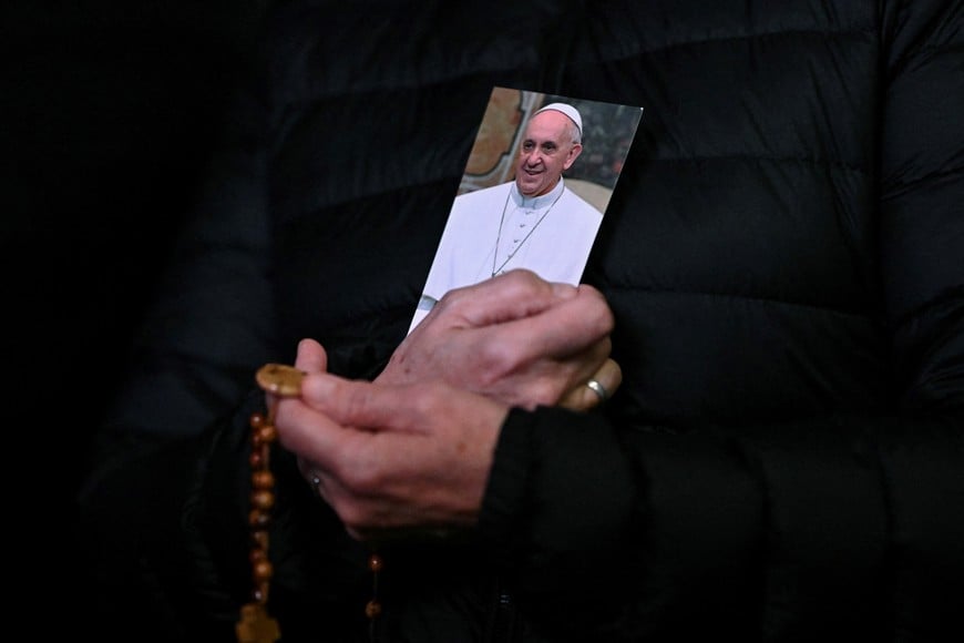 A person holds a picture of Pope Francis and a rosary during a prayer service at St. Peter's Square, as Pope Francis continues his hospitalization, at the Vatican, February 25, 2025. REUTERS/Dylan Martinez     TPX IMAGES OF THE DAY