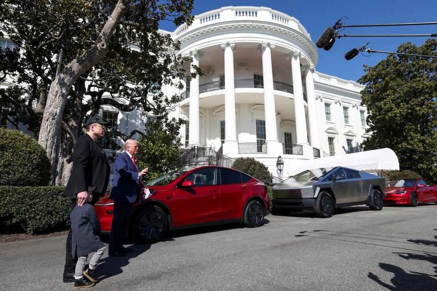 U.S. President Donald Trump talks to the media, next to Tesla CEO Elon Musk with his son X Æ A-12,  with Tesla cars in the background, at the White House in Washington, D.C., U.S., March 11, 2025. REUTERS/Kevin Lamarque